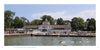 People enjoy swimming and relaxing by the Lakeside Pavilion, a light-colored building with a tower amid trees on a sunny day—capturing Midwest getaways featured in "Shores & Islands Ohio" by Schiffer Publishing, Ltd.