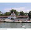 People enjoy swimming and relaxing by the Lakeside Pavilion, a light-colored building with a tower amid trees on a sunny day—capturing Midwest getaways featured in "Shores & Islands Ohio" by Schiffer Publishing, Ltd.