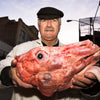 A man stands at dusk in New York City’s Meatpacking District, holding a large raw animal head, as seen on the cover of "Blood and Beauty" from Schiffer Publishing, Ltd.