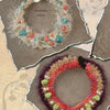 Felt, Fiber, and Stone by Schiffer Publishing, Ltd.: Two chunky hand-knitted bracelets on textured paper—one with white yarn, turquoise, coral & shell beads; the other in earth tones accented by green stones and pearls. A fresh twist on beaded jewelry.