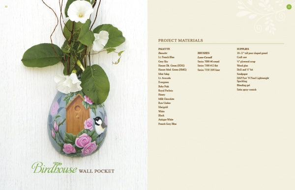Inspired by gourd painting, "Creating Wall Pockets" by Schiffer Publishing, Ltd. features an egg-shaped pocket painted with pink roses, green leaves, and a bird at a birdhouse. It holds greenery and white flowers; instructions and materials are provided.