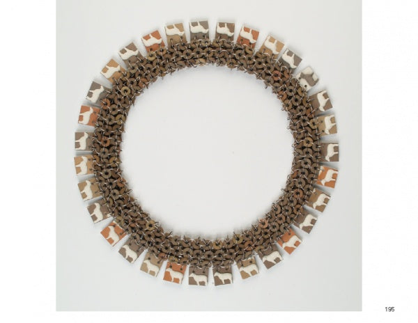 Art Jewelry Today 2 by Schiffer Publishing, Ltd. features a circular necklace of interlinked light brown and tan pieces with rectangular, cow-patterned charms spaced around the edge, showcased against a white background.